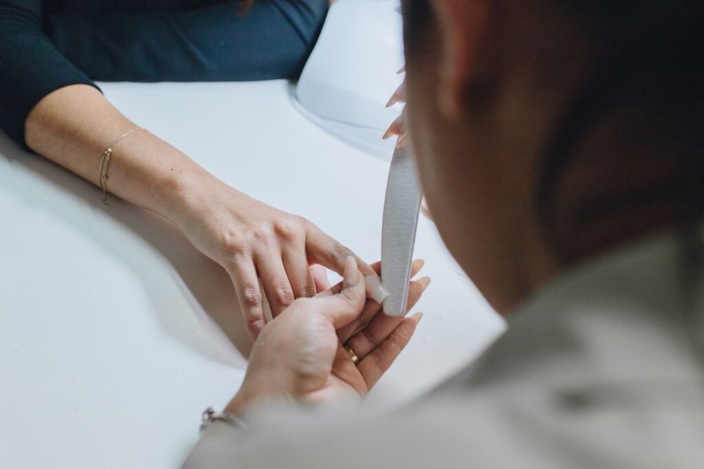 Close-up of a manicurist filing nails during a professional manicure session in a salon.